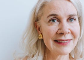 A smiling senior woman with earrings and necklace from a portrait session.