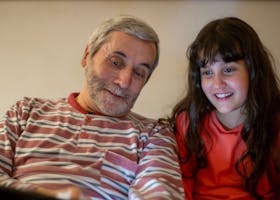 Smiling grandfather and granddaughter enjoying time together indoors, reflecting family love.